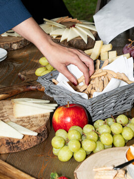 Hand Selecting Breadsticks from Rustic Cheese and Fruit Display