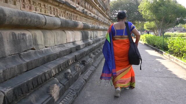 Indian woman in colorful saree walks around and explore Khajuraho Temple, UNESCO World Heritage Site, India.
