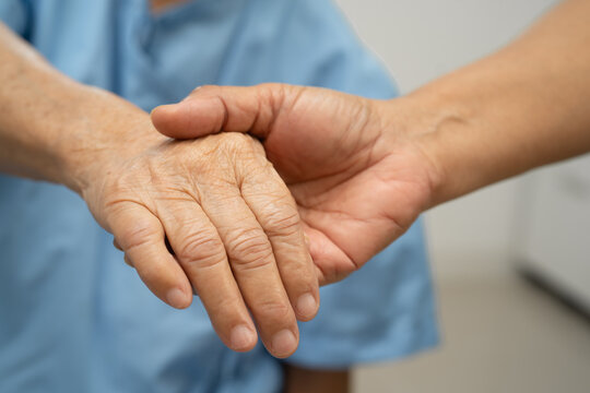 Caregiver holding hands Asian elderly woman patient, help and care in hospital.
