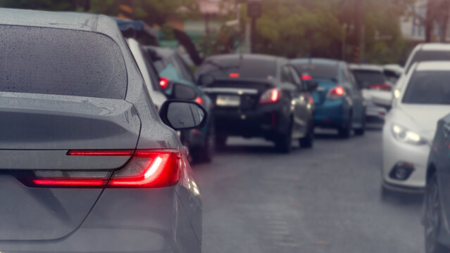 Rear view perspective of cars stuck in a traffic jam on an urban asphalt road. During the daytime emphasizing the busy commute. Traffic jam is visible as a curved line in the distance ahead.