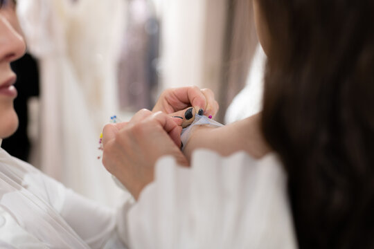 Dressmaker and female customer fitting and adjusting dress