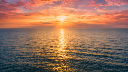 Obraz premium Beautiful sunset over the ocean with vibrant clouds, golden sunlight, and calm sea.