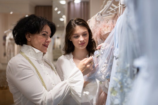 Female Atelier owner helping woman in choosing dress