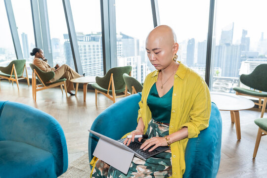 Asian Woman Working on Laptop in Modern Office Overlooking City