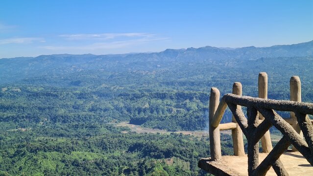 Scenic Landscape View of Lush Green Tropical Forest and Distant Blue Mountains from a Wooden Terrace