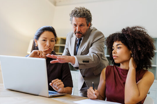 Professionals collaborating on laptop during business meeting