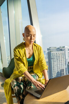 Woman Working on Laptop in High-Rise Office Building During Daytime