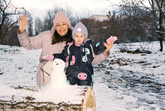 Mom and little girl playing in a winter park.