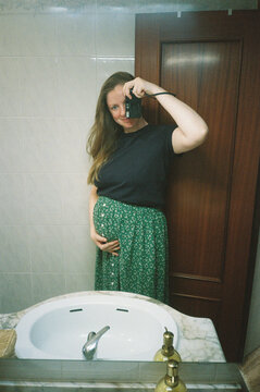 Pregnant Woman Taking Mirror Selfie With Vintage Film Camera