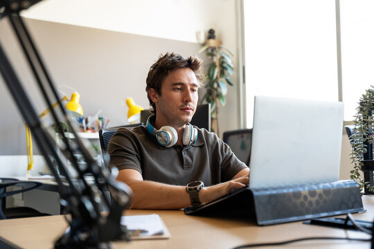 Young man concentrating on laptop in modern office