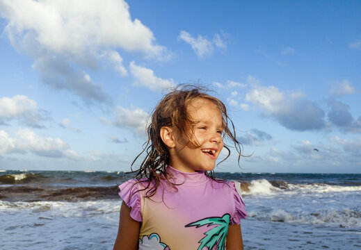 Happy child portrait in ocean waves on sunset beach