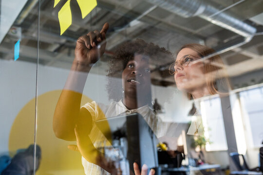 Diverse businesswomen brainstorming ideas on glass board