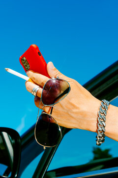 against a vast blue sky, a man uses his smartphone from a car window
