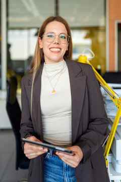 Businesswoman smiling while holding digital tablet in office