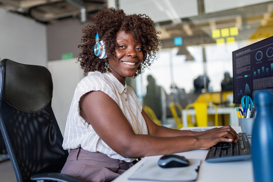 Happy black woman working on computer in office