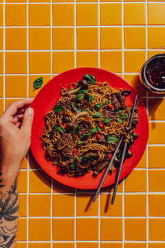 Person eating beef stir fry noodles with chopsticks 