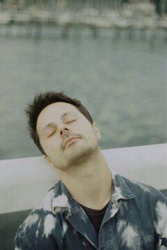 Man Resting Head On Bridge Railing