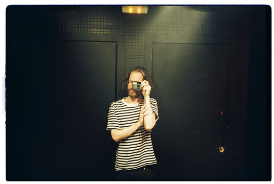 Man Takes Self Portrait in a Dark Room With Black Doors