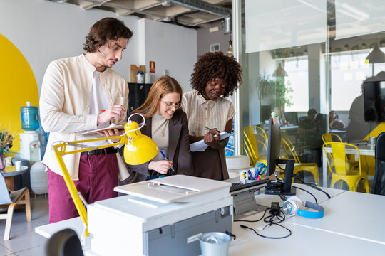 Diverse young colleagues collaborating on a document in office
