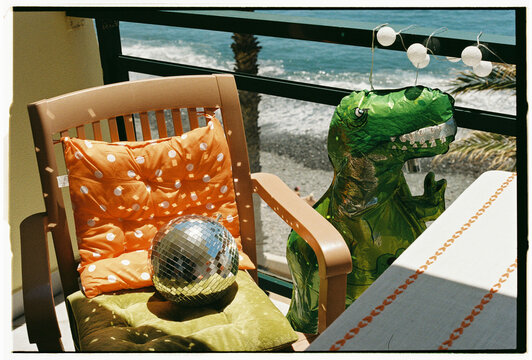 Inflatable T-Rex and Disco Ball on Balcony Over Pebble Beach