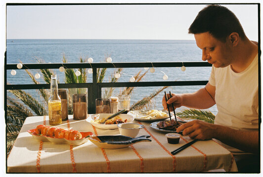 Man Eating with Chopsticks on Oceanfront Balcony, Funchal