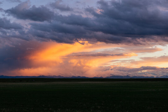 Sunset Over a Field With Clouds and Mountains in the Distance