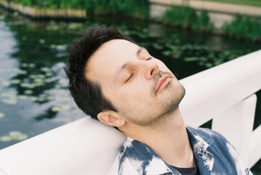 Man Resting Head On Bridge Railing