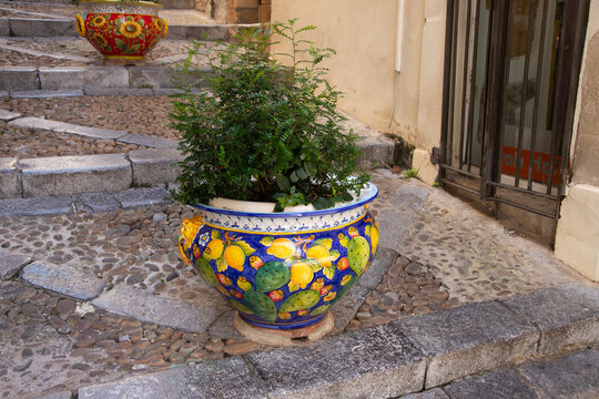 Charming Italian alleyway with decorative planters and stone steps in Cefalu, Sicily, Italy.