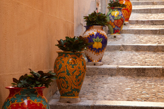 Charming Italian alleyway with decorative planters and stone steps in Cefalu, Sicily, Italy.