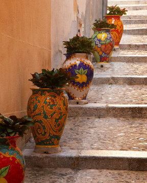 Charming Italian alleyway with decorative planters and stone steps in Cefalu, Sicily, Italy.