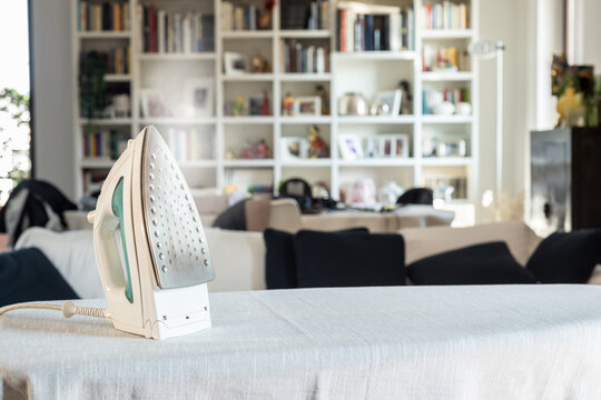 Modern iron with steam on ironing board at home.
