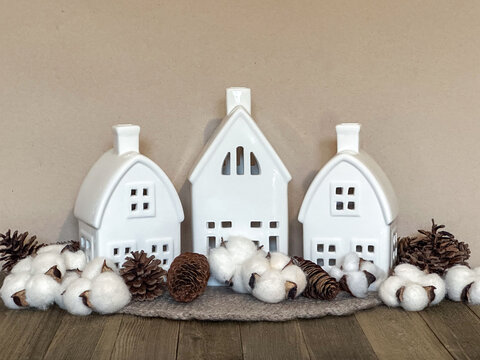 Minimalist ceramic village houses styled with cotton bolls and pinecones in a neutral palette, creating a cozy Scandinavian display for autumn, winter, Thanksgiving and Christmas.