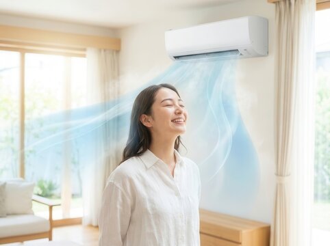 A woman stands under an air conditioner in a room and enjoys the coolness