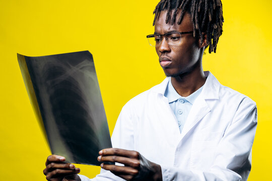 African american doctor concentrating on a medical x-ray film, reviewing lung condition for an accurate health diagnosis