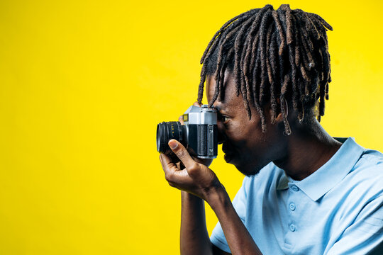 African american photographer focusing through the viewfinder of an old film camera, capturing special moments and memories