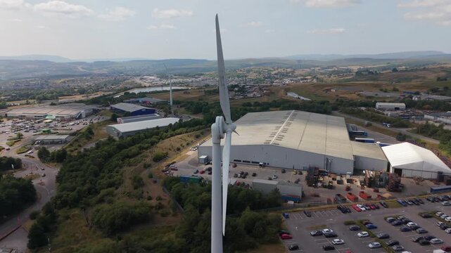 Penygarnddu, Merthyr Tydfil, Wales, United Kingdom - July 23, 2026: Cinematic drone orbit around a large wind turbine at a wind farm near Merthyr Tydfil, showcasing rotating blades, renewable energy i