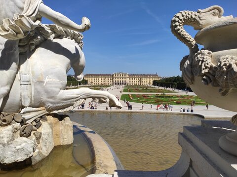 Beautiful formal gardens of Sch&ouml;nbrunn Palace with vibrant floral patterns, Neptune Fountain and the iconic Gloriette overlooking the park in Vienna, Austria.