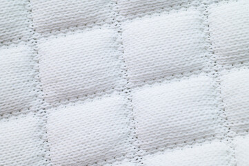 Obraz premium Close-up of white quilted fabric with square stitched pattern and soft texture