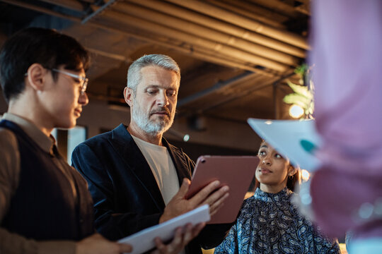 Business team discussing project on tablet in modern office