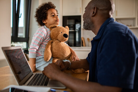 Father working from home, talking with child in kitchen