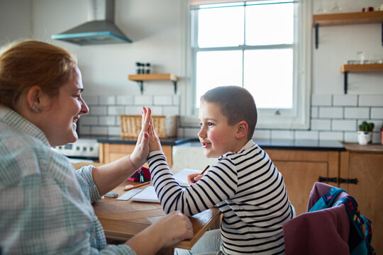 Parent helping boy with homework at kitchen table