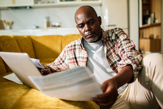 Man reviewing household bills on laptop at home