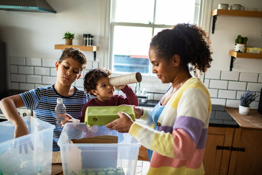 Mother and children sorting recyclables in home kitchen