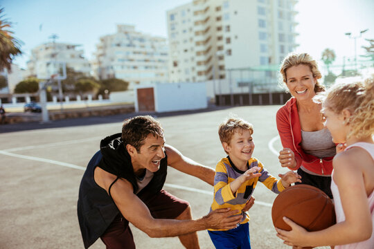 Family with kids playing basketball on urban outdoor court