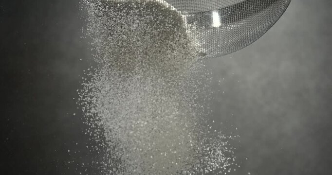 Flour sifts through a sieve creating soft powder cloud in slow motion
