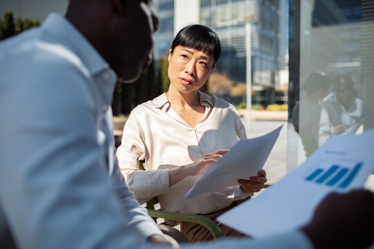 Business colleagues discussing reports outdoors at office