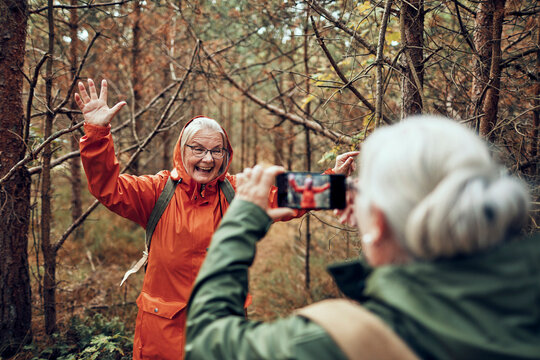 Senior women hiking in forest, taking smartphone photo