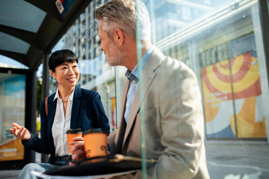 Business colleagues chatting at a city bus stop