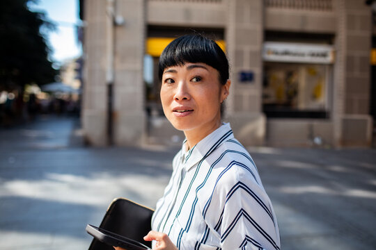 Confident businesswoman with tablet on sunny city street