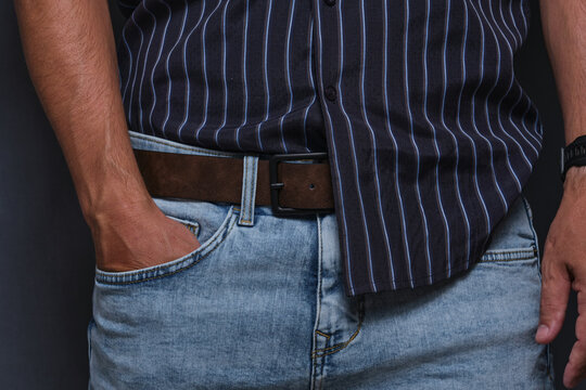 Close up man in light blue jeans and striped shirt with hand tucked into his pocket.